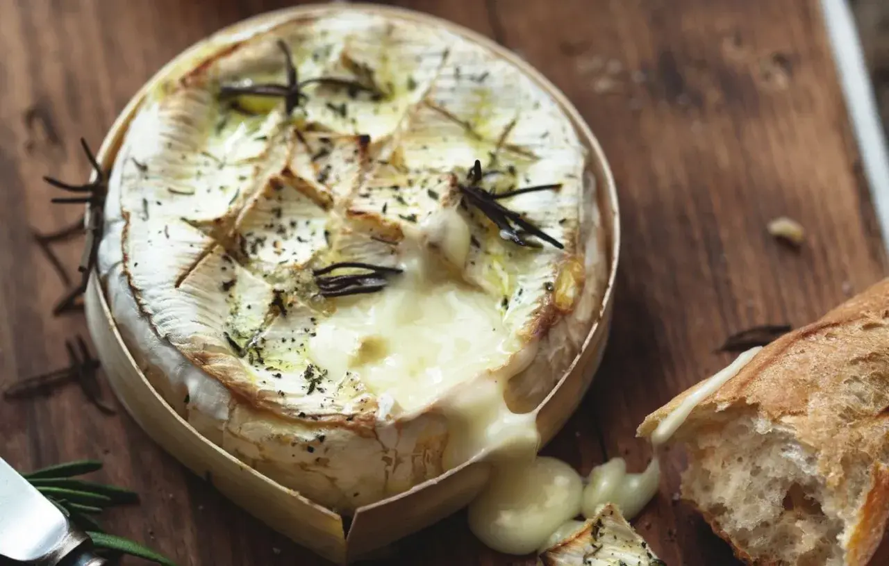 Camembert fondant au romarin, prêt à être dégusté avec une baguette croustillante. Le meilleur camembert au barbecue pour un moment gourmand.