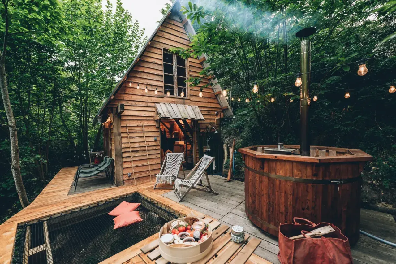 Une cabane dans les arbres dans les Landes, avec un bain nordique fumant et un hamac invitant. Parfait pour une escapade nature.
