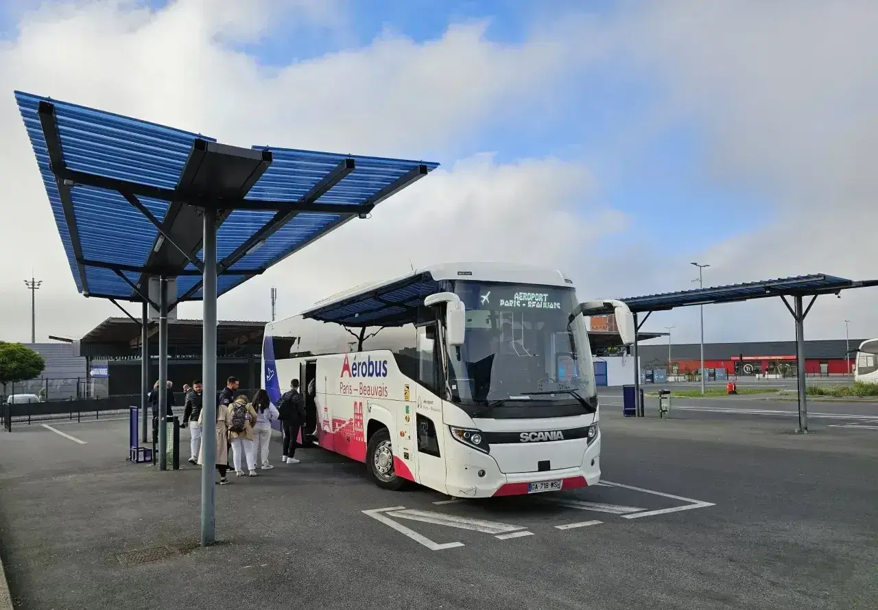 Autobus Aerobus z napisem "Paris-Beauvais" czeka na pasażerów pod niebieskim zadaszeniem.