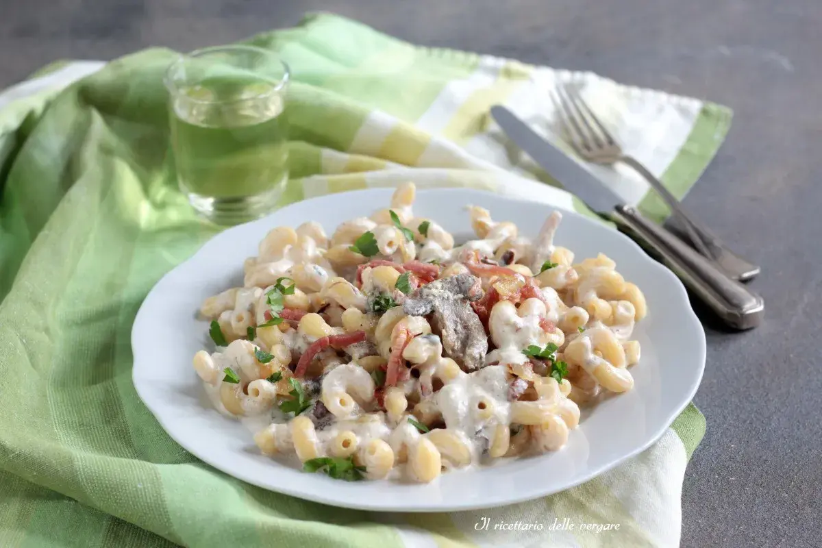 Piatto di pasta alla boscaiola cremosa con funghi e pancetta, guarnita con prezzemolo fresco.