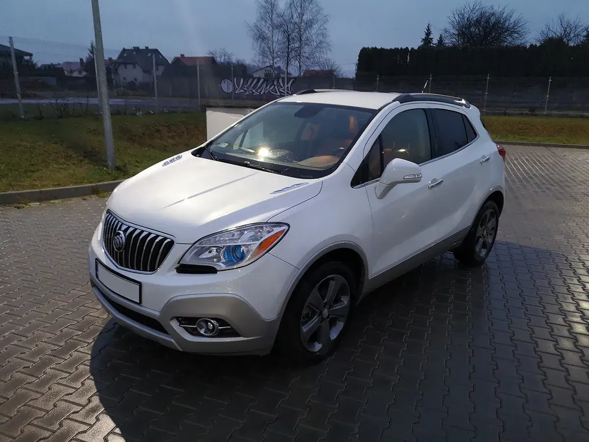 Biały Buick Encore stoi na mokrej, brukowanej nawierzchni.