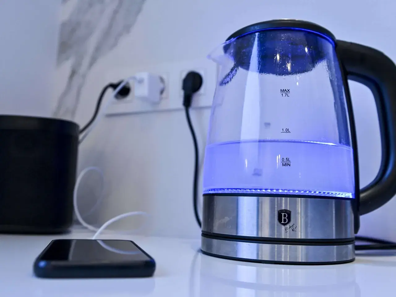 Ein beleuchteter Wasserkocher steht neben einem Smartphone. Ein Tipp: Wasserkocher entkalken Backpulver hilft gegen Kalk.