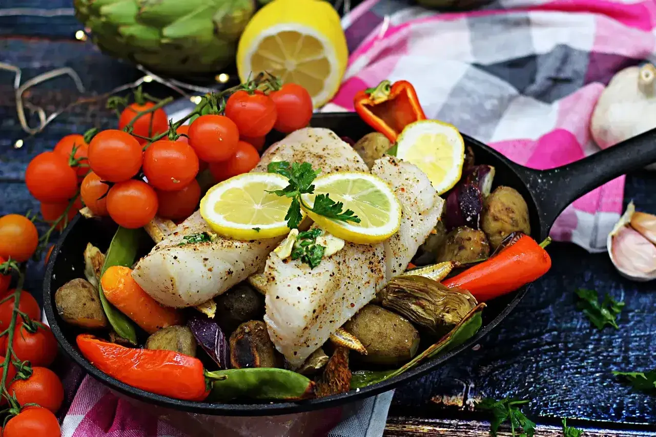 Pyszny halibut ryba pieczony z warzywami i cytryną na patelni.