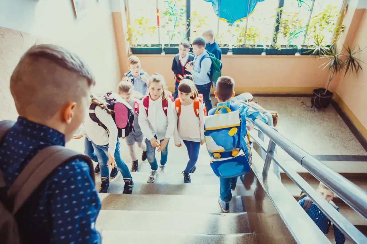 Dzieci z plecakami schodzą po schodach, jakby wracały do domu po lekcjach. Może to dzień, w którym weszła w życie ustawa Kamilka, zapewniająca im bezpieczeństwo.