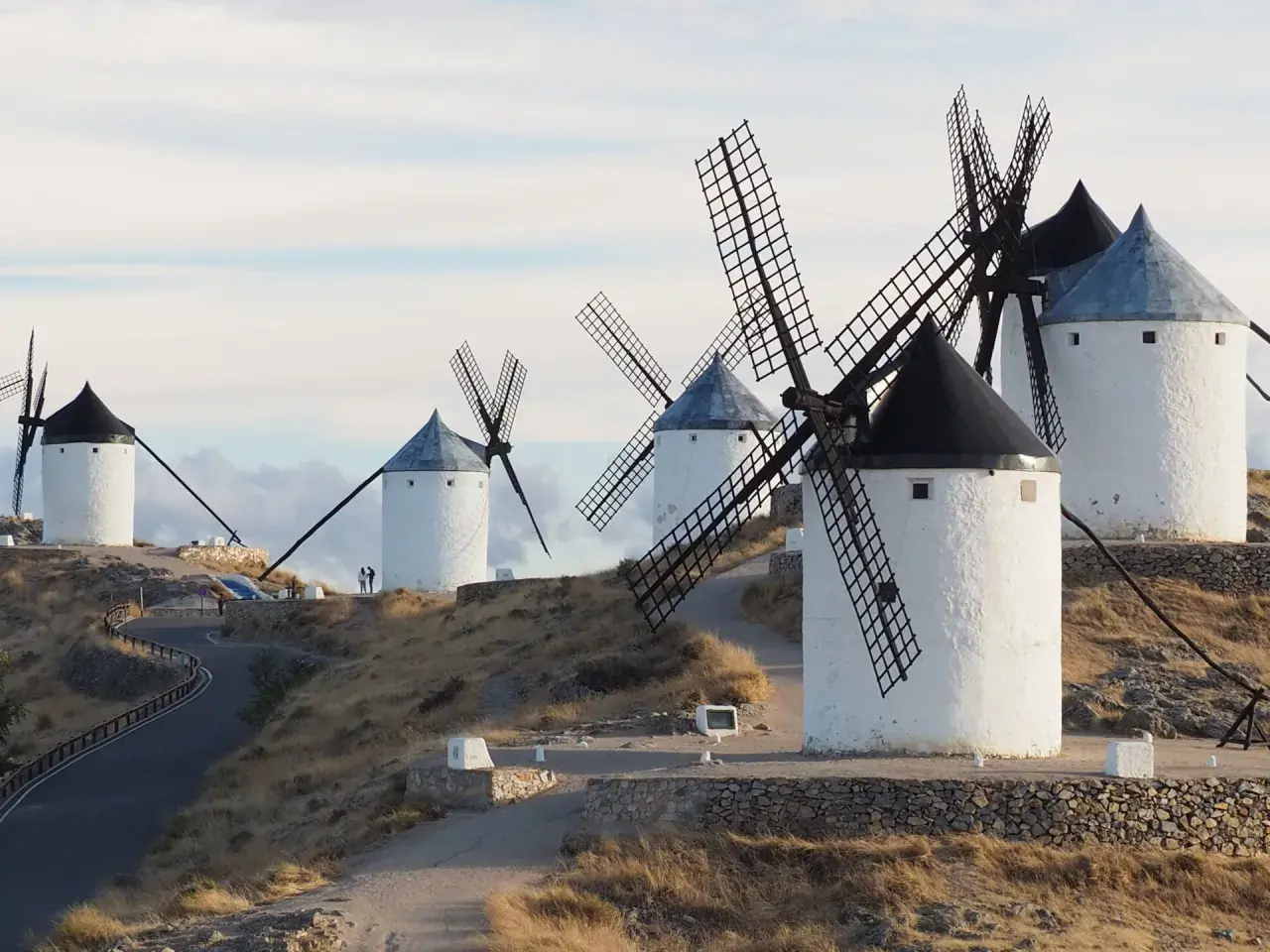 Los icónicos molinos de Consuegra se alzan sobre una colina, sus aspas recortadas contra un cielo nublado.