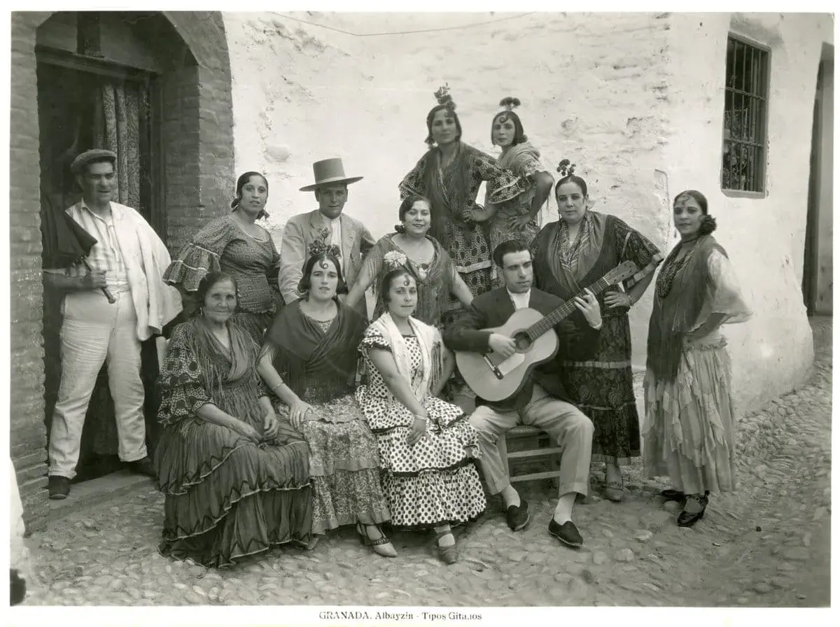 Grupo de gitanos en Granada, con un hombre tocando la guitarra. Captura la esencia del significado del flamenco.