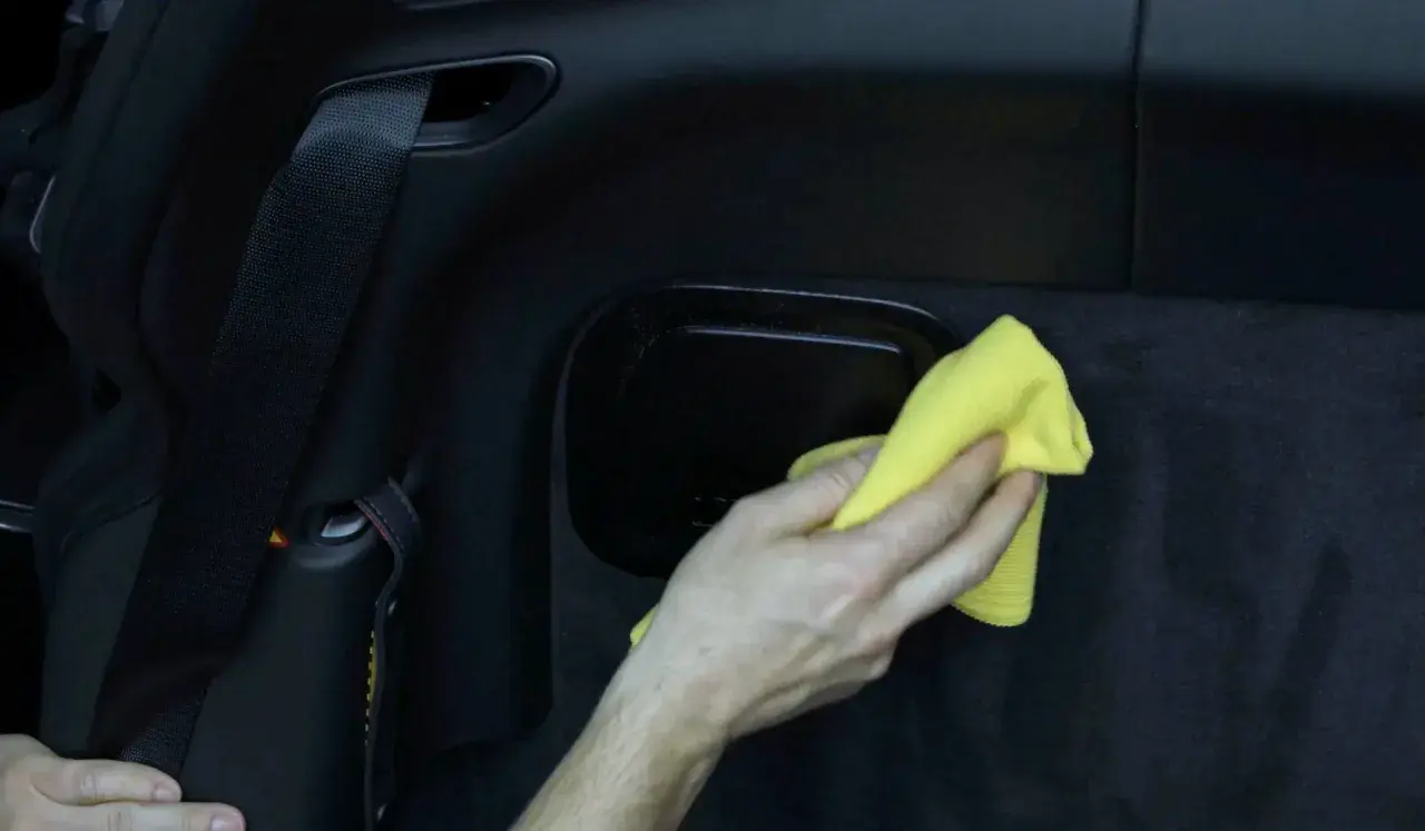 Hand poliert matten Kunststoff im Auto mit gelbem Tuch.