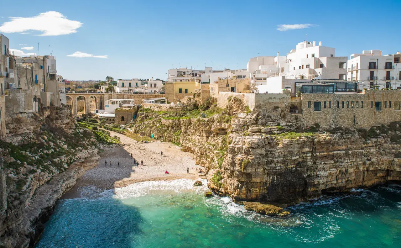 Un'idea per il tuo itinerario Puglia 7 giorni in macchina: la costa rocciosa di Polignano a Mare con la sua spiaggia e le case bianche a picco sul mare.