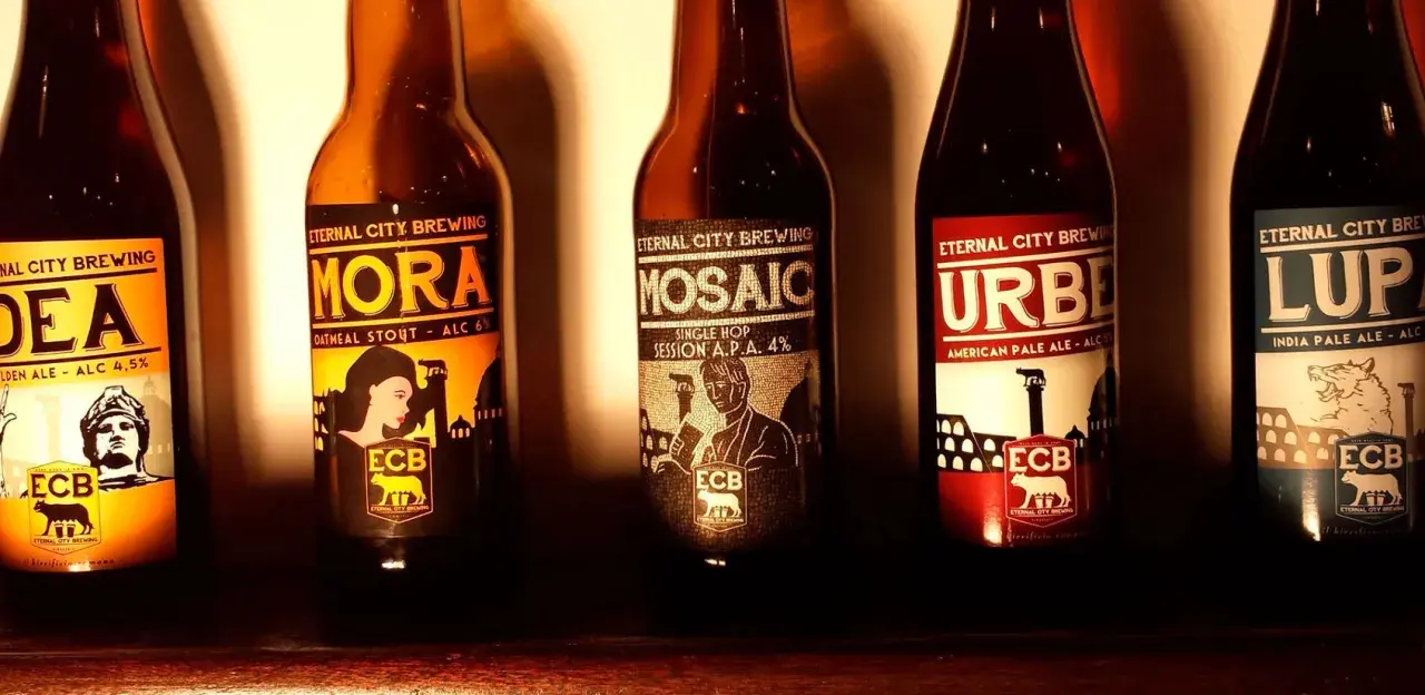 Cinque bottiglie di birra artigianale di Eternal City Brewing, con etichette raffiguranti monumenti e figure iconiche.