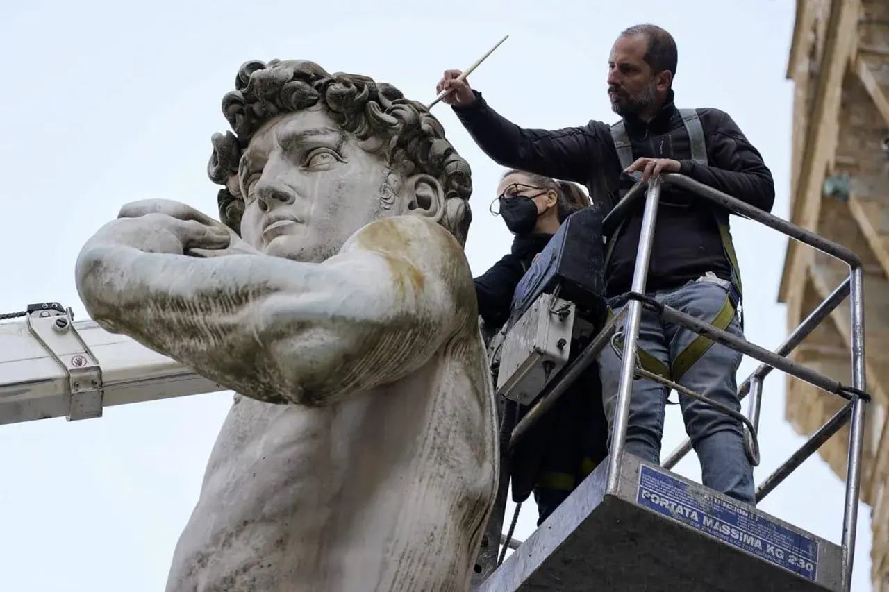 Restauratoren arbeiten auf einer Hebebühne am David von Michelangelo. Wo steht der David von Michelangelo? In Florenz, Italien.