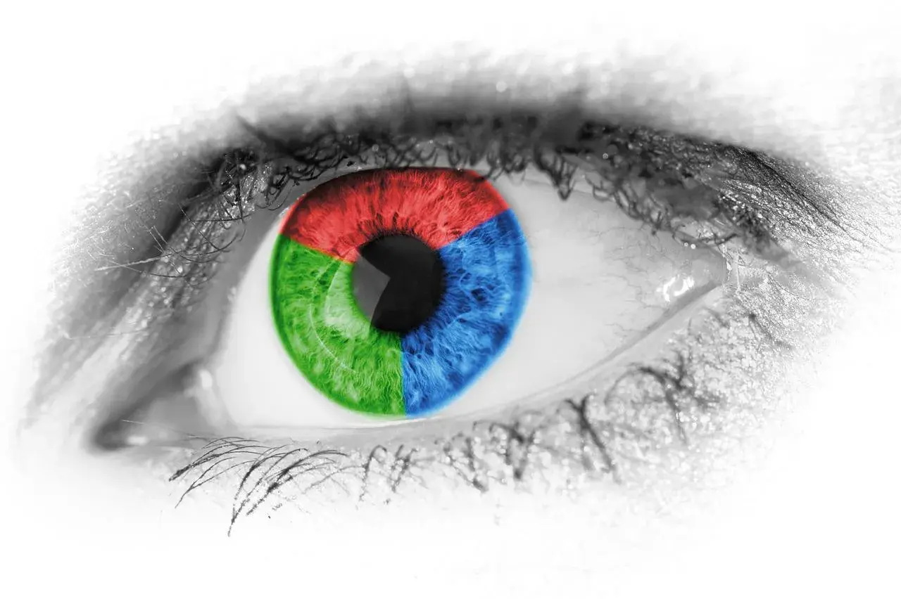 Occhio con iride divisa in settori rosso, verde e blu colore primario. Ciglia nere su sfondo bianco.