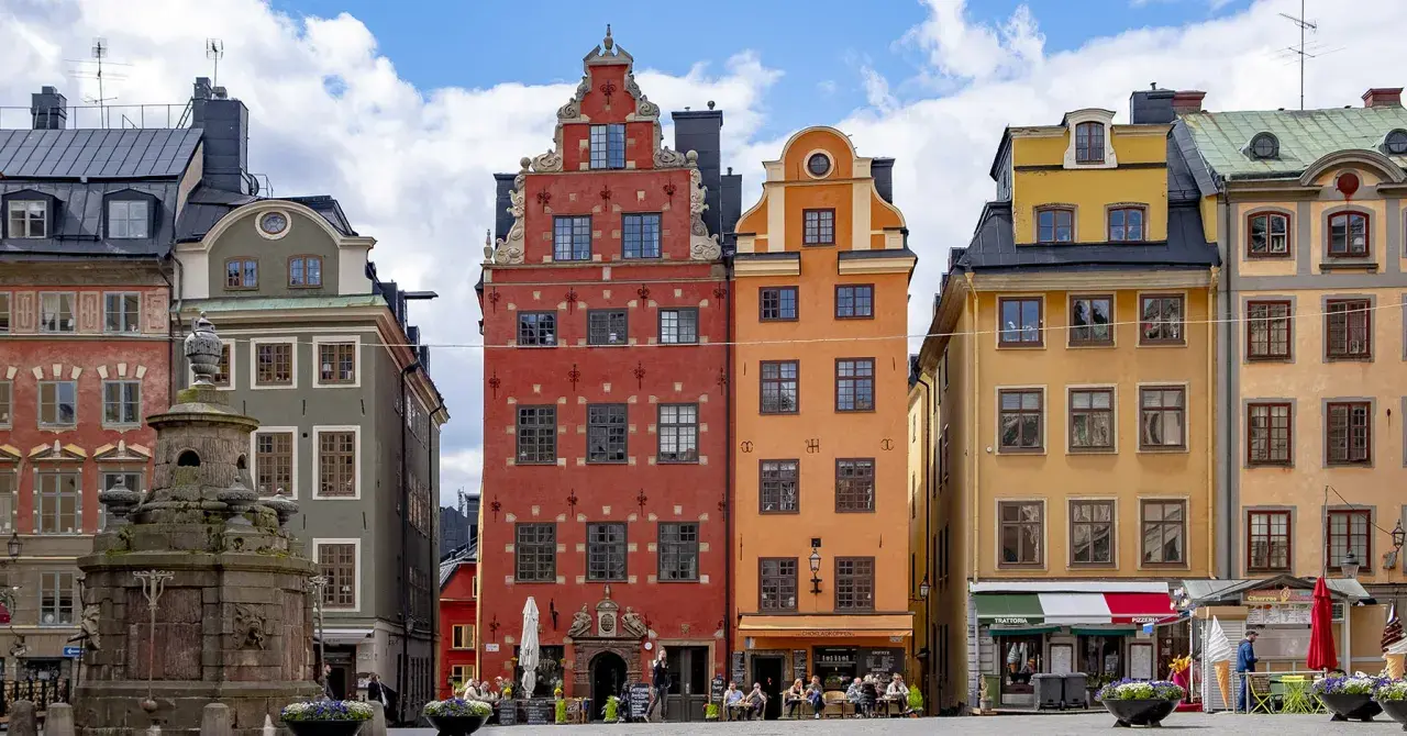Färgglada hus på Stortorget, Stockholm sommar. En fontän står framför de gamla byggnaderna.