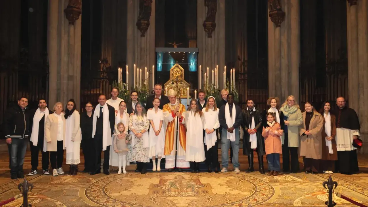 Gruppe feiert den Osternacht Gottesdienst mit Bischof in festlicher Robe vor Kerzenlicht und Altar.