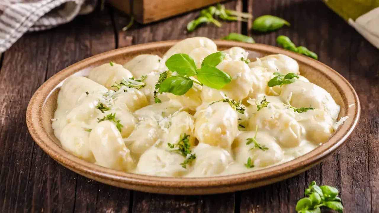 Pyszne gnocchi z kurczakiem w kremowym sosie, posypane parmezanem i świeżą bazylią. Idealne danie na obiad.
