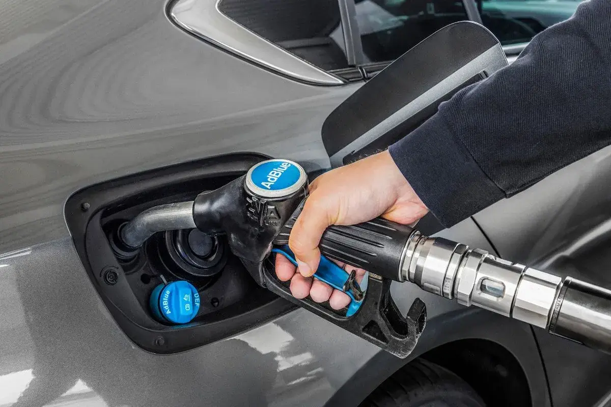 Persona repostando AdBlue en su coche. La cantidad de kilómetros que dura el AdBlue varía según el vehículo y el estilo de conducción.