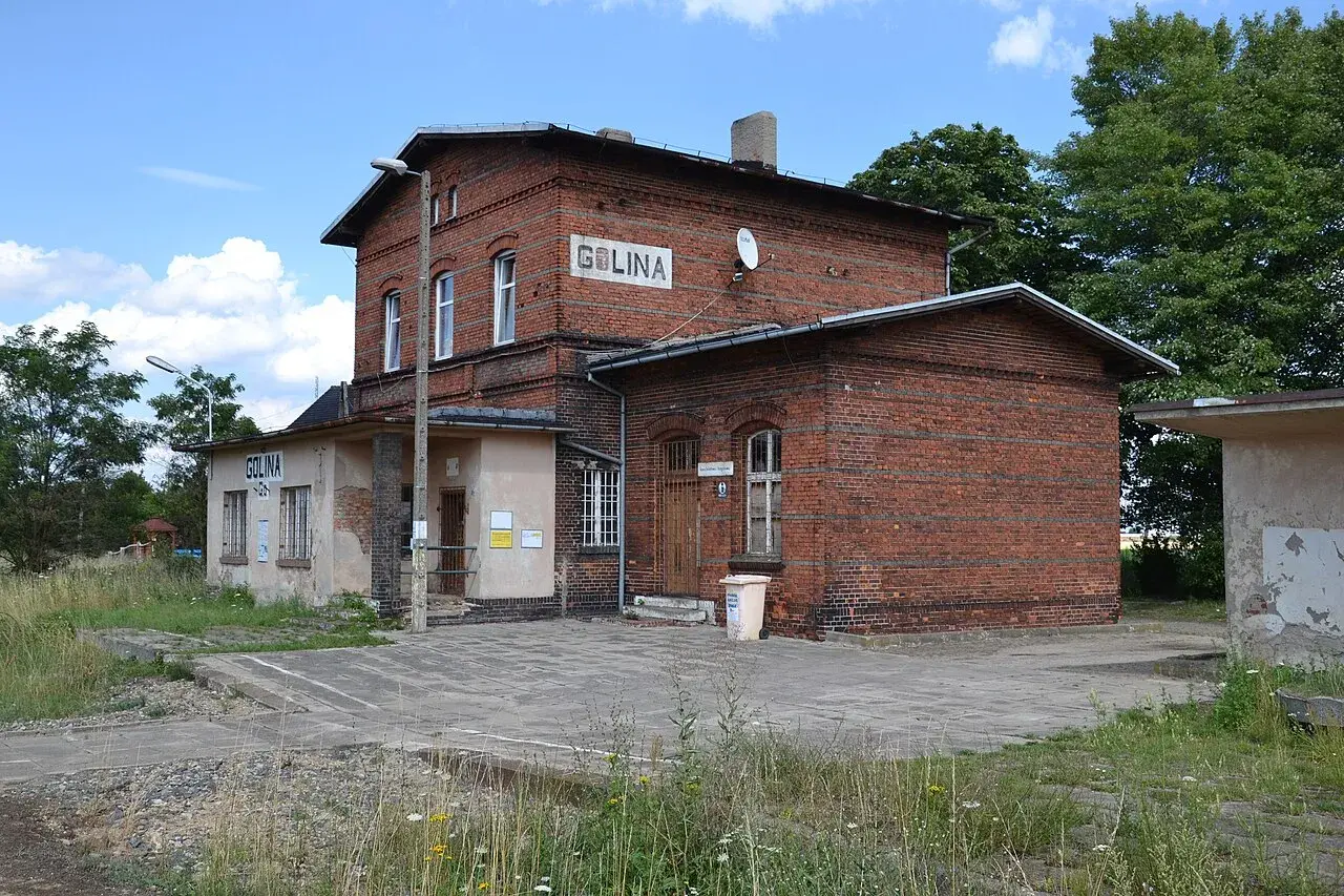 Stary ceglany budynek dworca kolejowego Golina z napisem "GOLINA" na fasadzie.