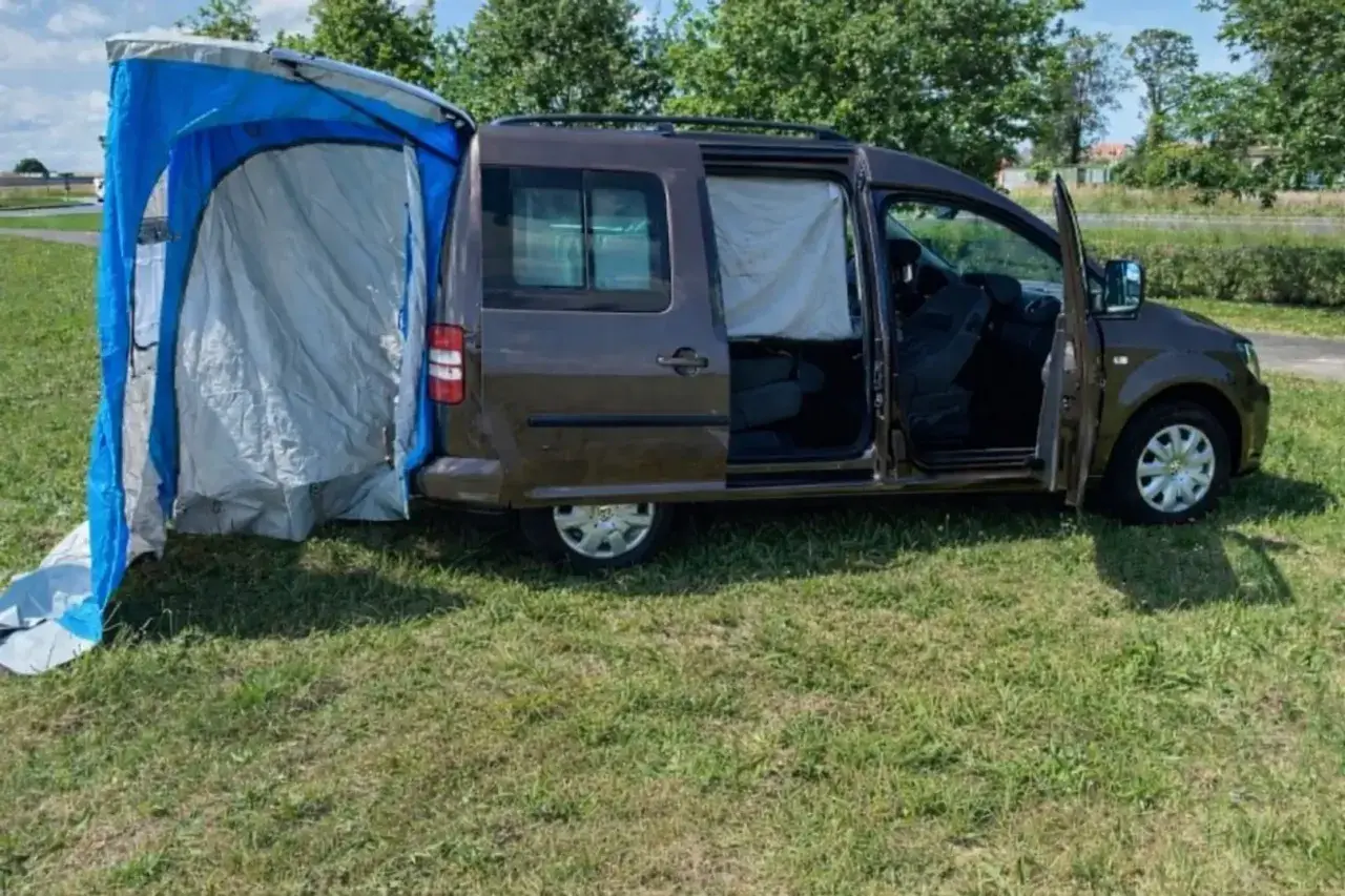 Un caddy tramper aménagé avec une tente latérale bleue et grise, prêt pour l'aventure en plein air.