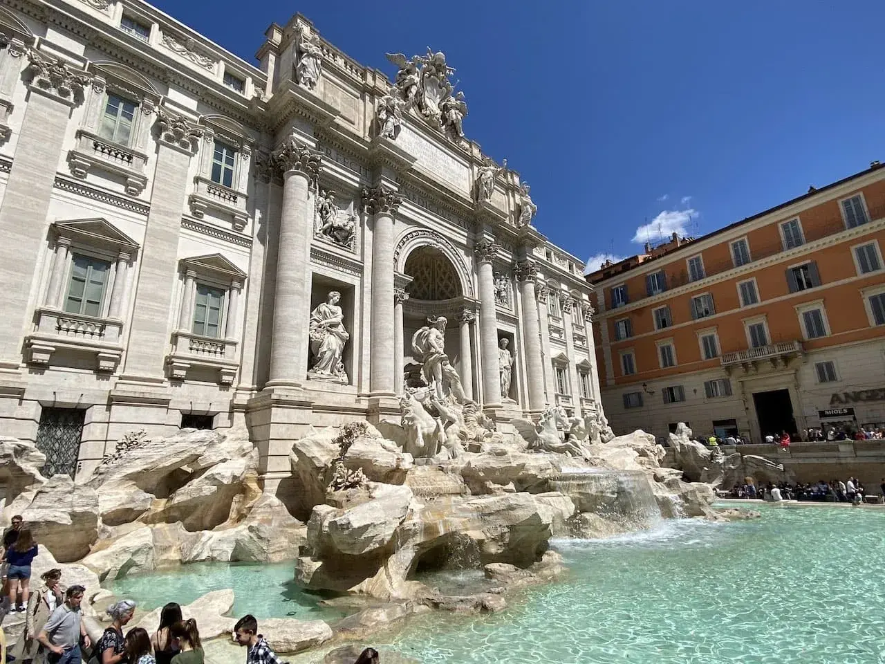 Fontaine de Trevi, un chef-d'œuvre baroque à Rome, Italie, avec des touristes admirant sa splendeur sous un ciel bleu.