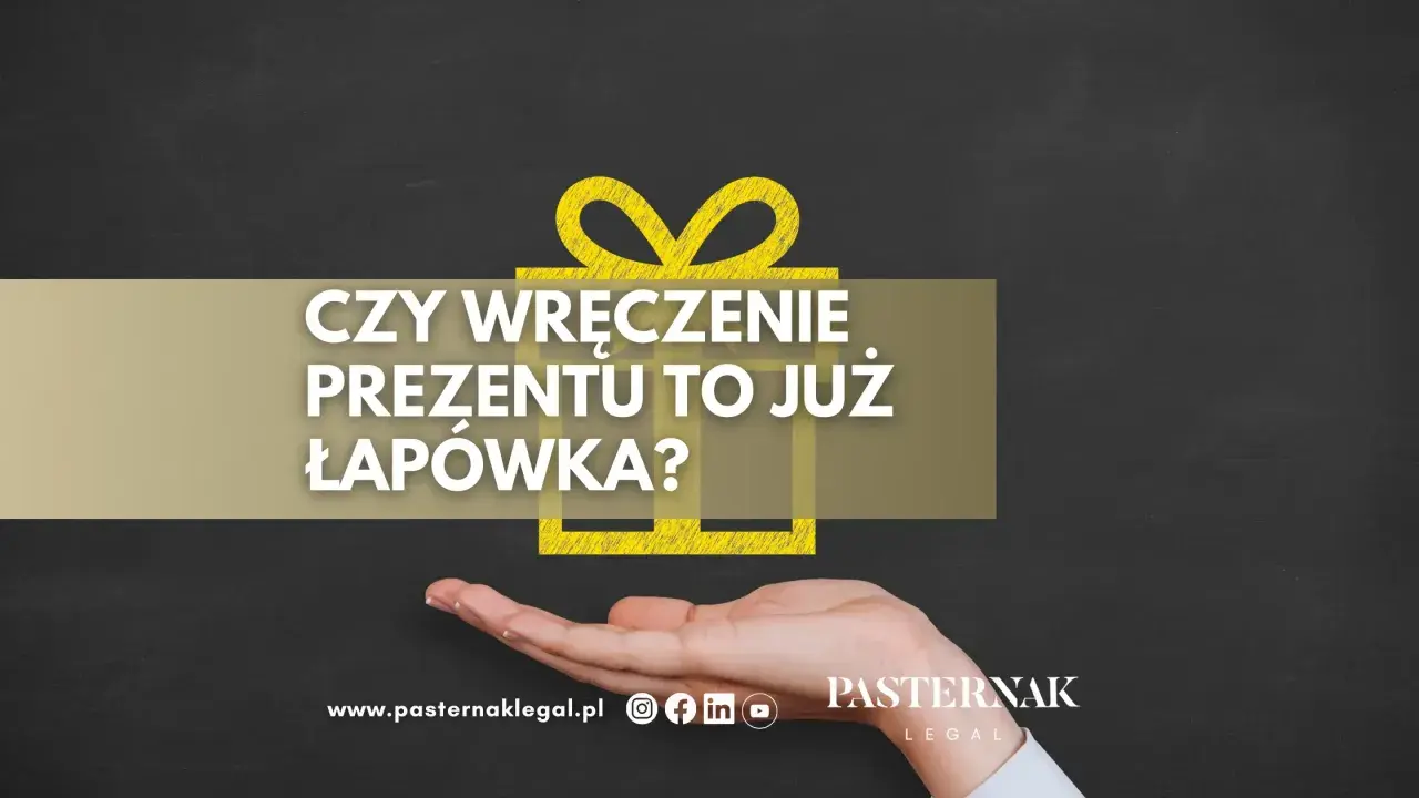 Czy wręczenie prezentu to już łapówka? Dłoń trzyma symbol prezentu, a tekst pyta o granicę między gestem a nielegalnym działaniem.