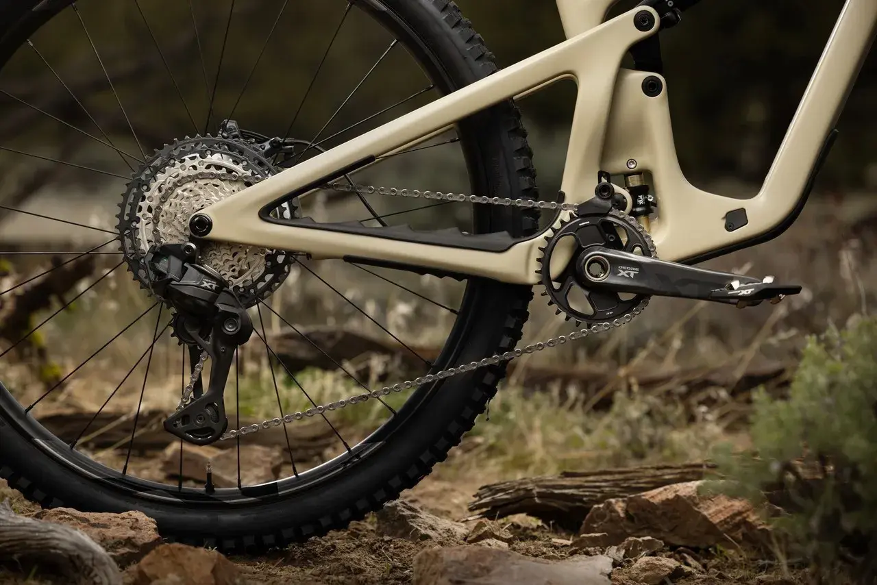Tylna przerzutka i kaseta napędu rowerowego Shimano Deore LX na piaskowym fullu, gotowe na terenowe wyzwania.