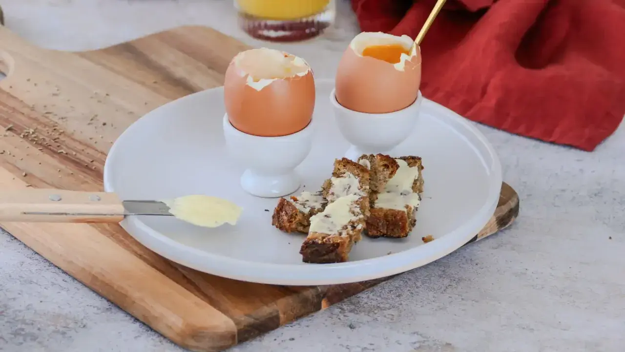 Deux oeufs à la coque, prêts à être dégustés avec des mouillettes de pain beurrées. Un petit-déjeuner simple et réconfortant.