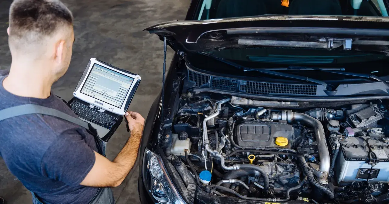 Mechanik diagnozuje przedmuchy w silniku za pomocą komputera.
