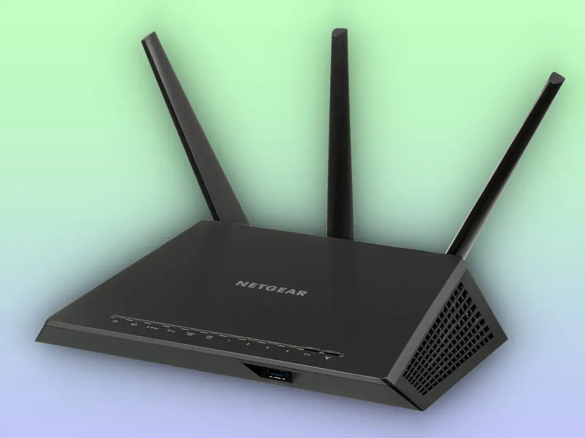 Un enrutador Netgear negro con tres antenas, esencial para tu conexión a internet.