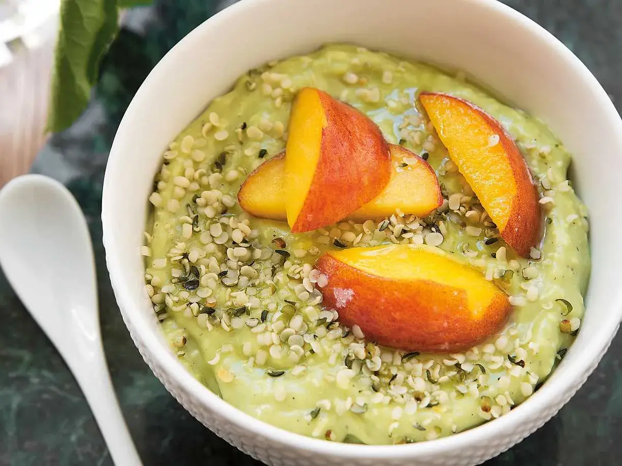Grön smoothiebowl med avokado, toppad med persikoklyftor och hampafrön. Ett enkelt och gott avokado recept.