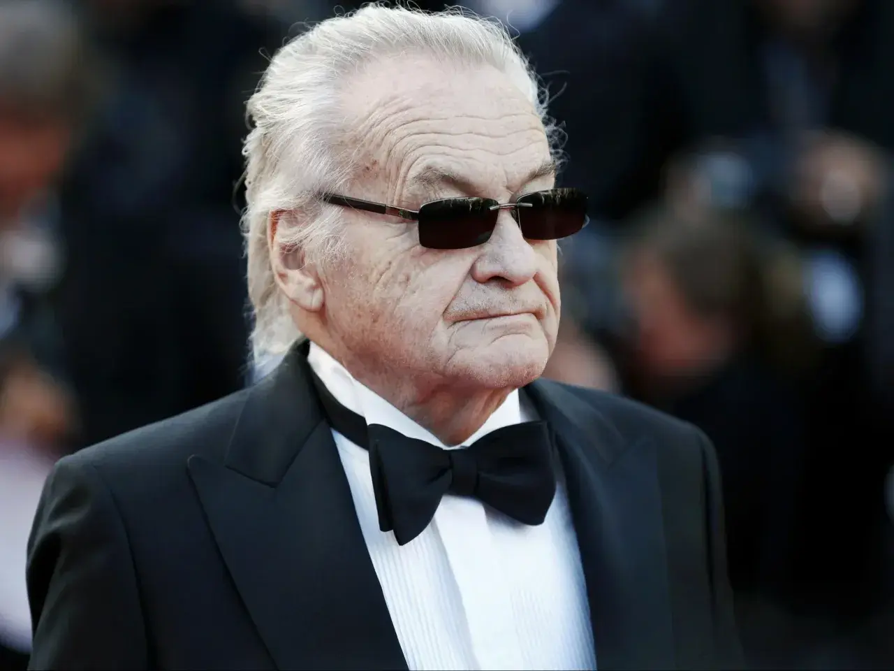 Jerzy Skolimowski w smokingu i okularach przeciwsłonecznych, ikona polskiego kina.