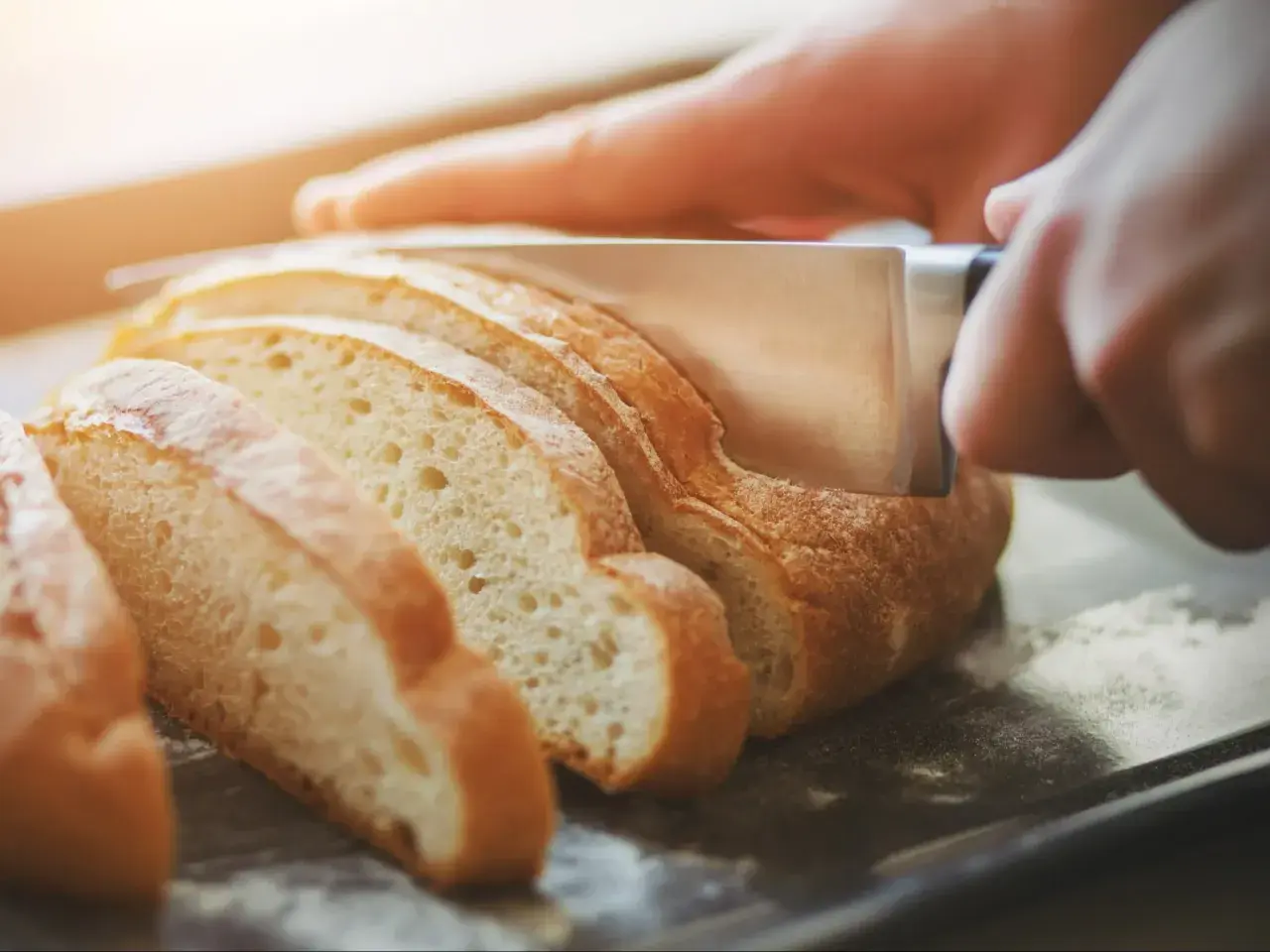 Krojony chleb na desce, gotowy, by dowiedzieć się, jak podgrzać chleb w piekarniku.