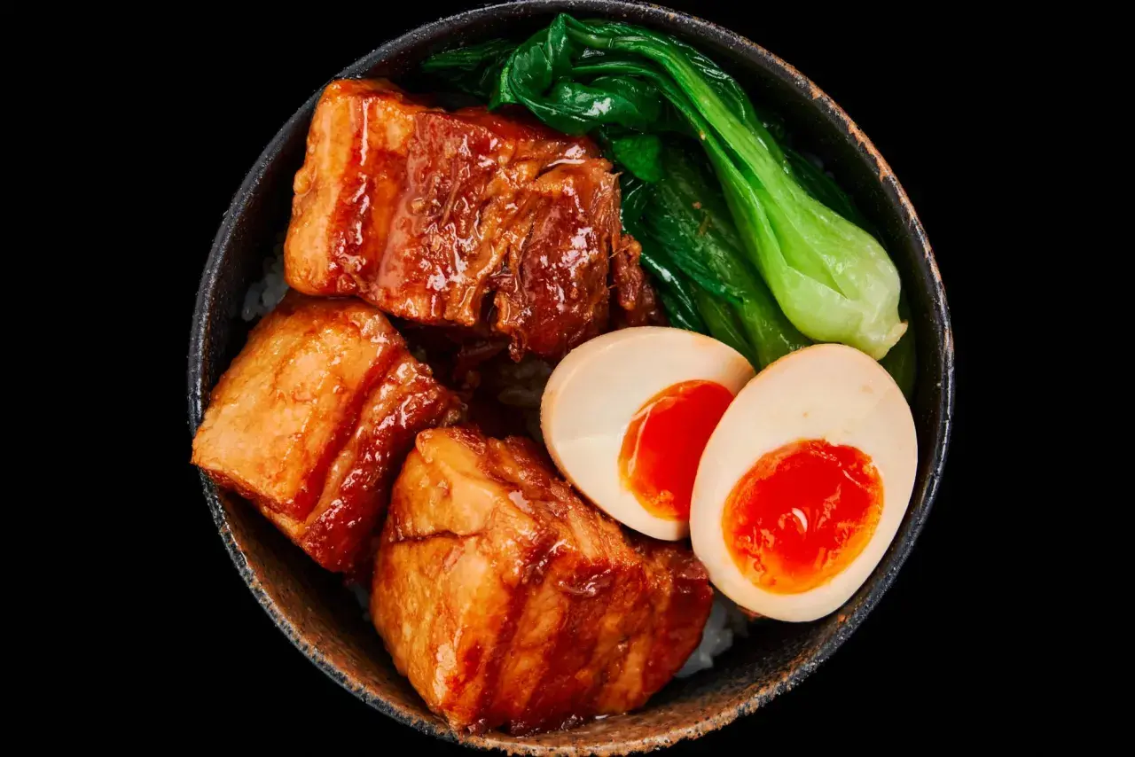 A bowl of Japanese pork belly with rice, bok choy, and a soft-boiled egg.