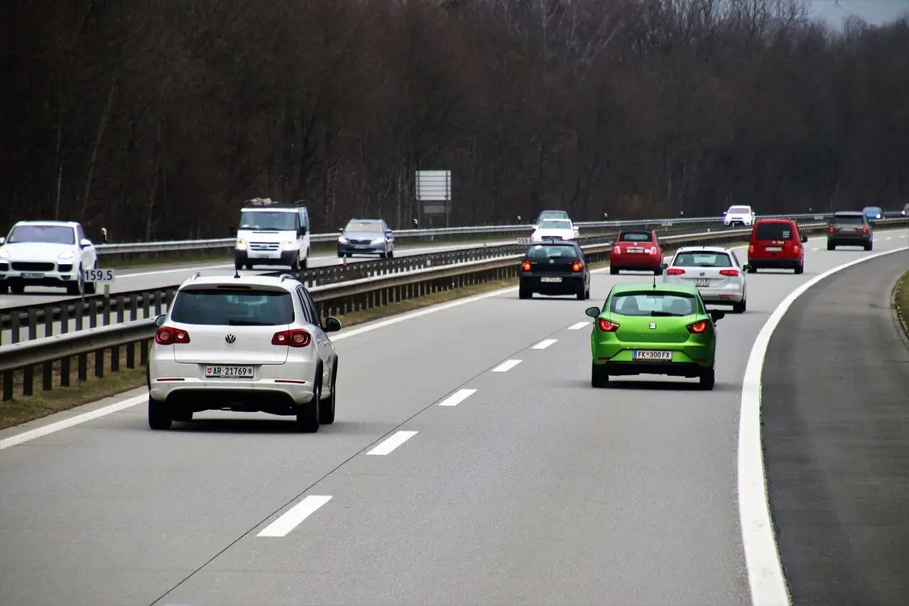 Ruch na autostradzie. Kierowca zielonego auta zastanawia się, jaki mandat za wymuszenie pierwszeństwa, gdyby to zrobił.