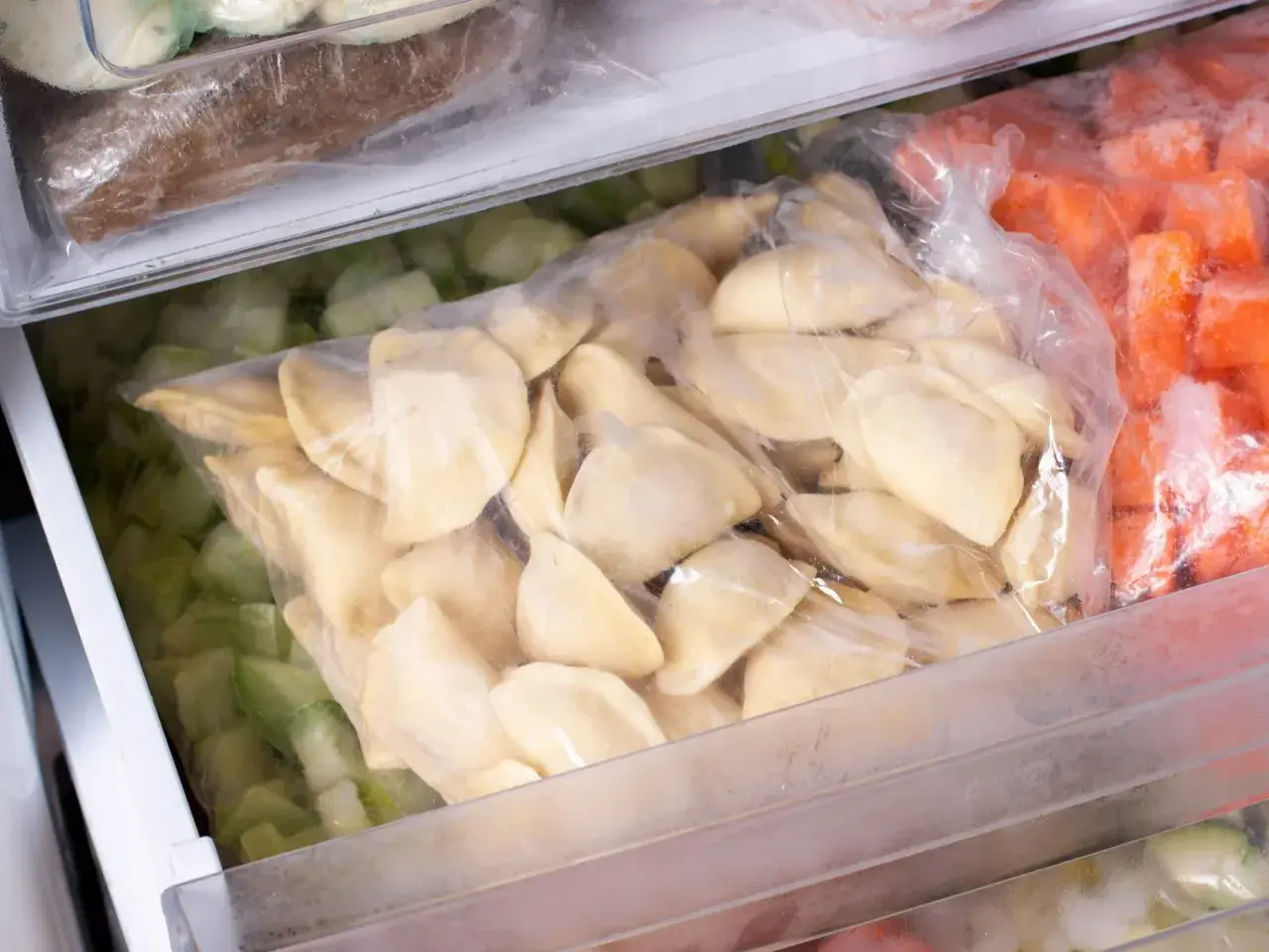 Jak mrozic domowe pierogi? W zamrażarce leżą woreczki z pierogami, mrożonymi warzywami i innymi produktami.