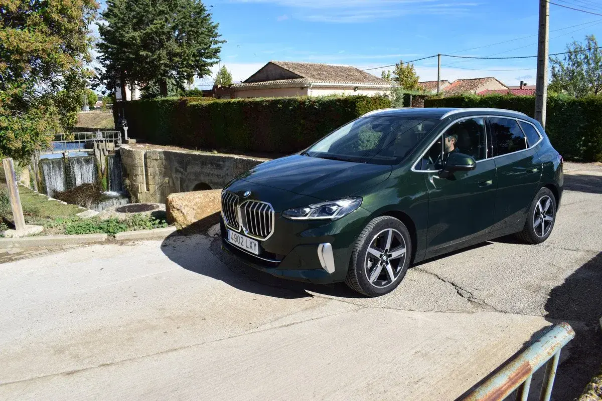 Un BMW Serie 2 Active Tourer verde oscuro aparcado cerca de una esclusa de agua. ¿Problemas con el coche o solo una parada escénica?