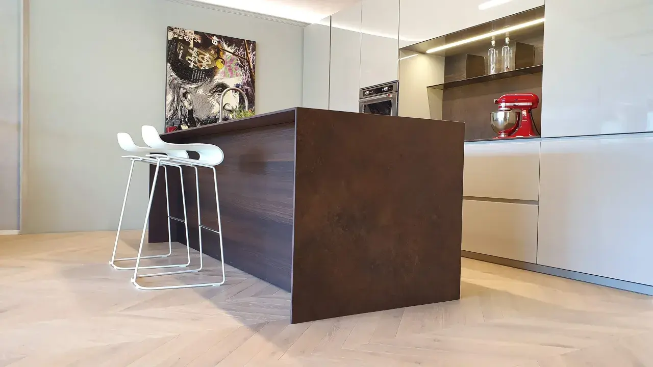 Moderno montaggio cucina con isola centrale in legno scuro, sgabelli bianchi e quadro artistico.