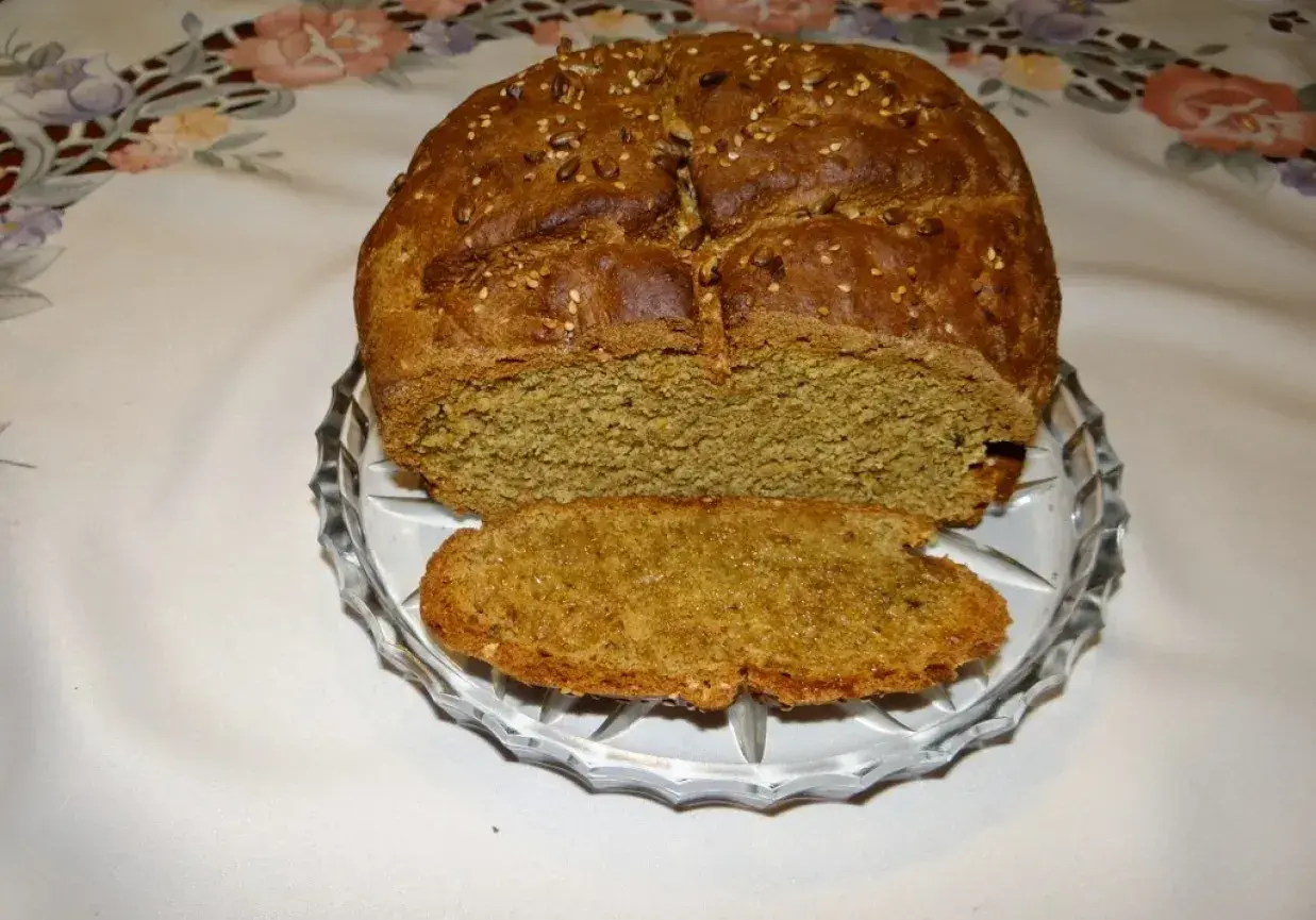 Pyszny, domowy chleb pytlowy z ziarnami na wierzchu, pokrojony na talerzyku.
