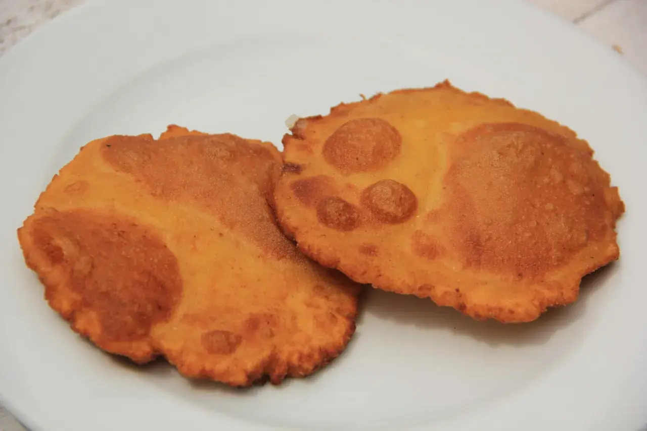 Dos tortos asturianos dorados y crujientes sobre un plato blanco.