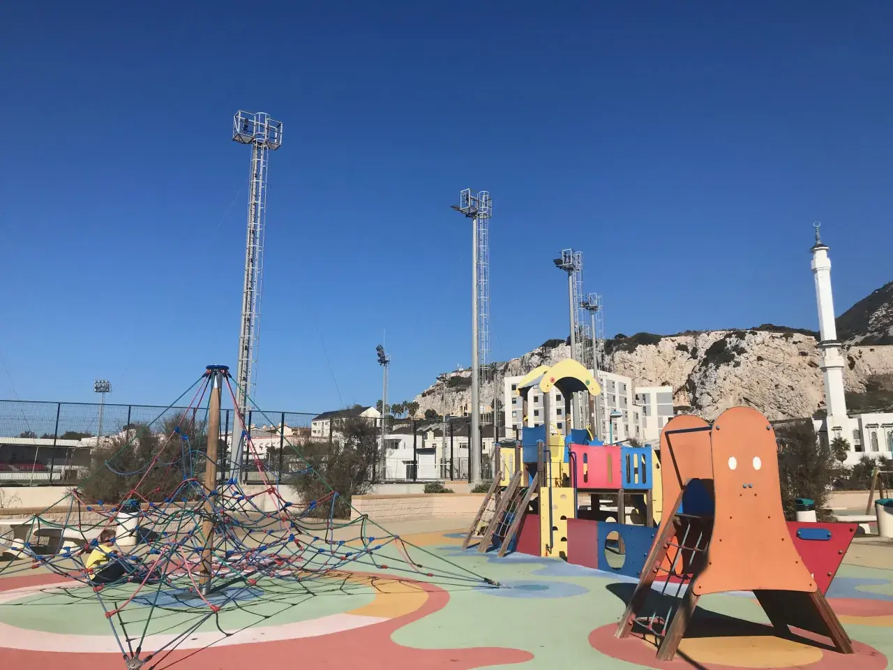 Parque infantil colorido con el Peñón de Gibraltar al fondo. ¡Un lugar ideal que hacer en Gibraltar con niños!