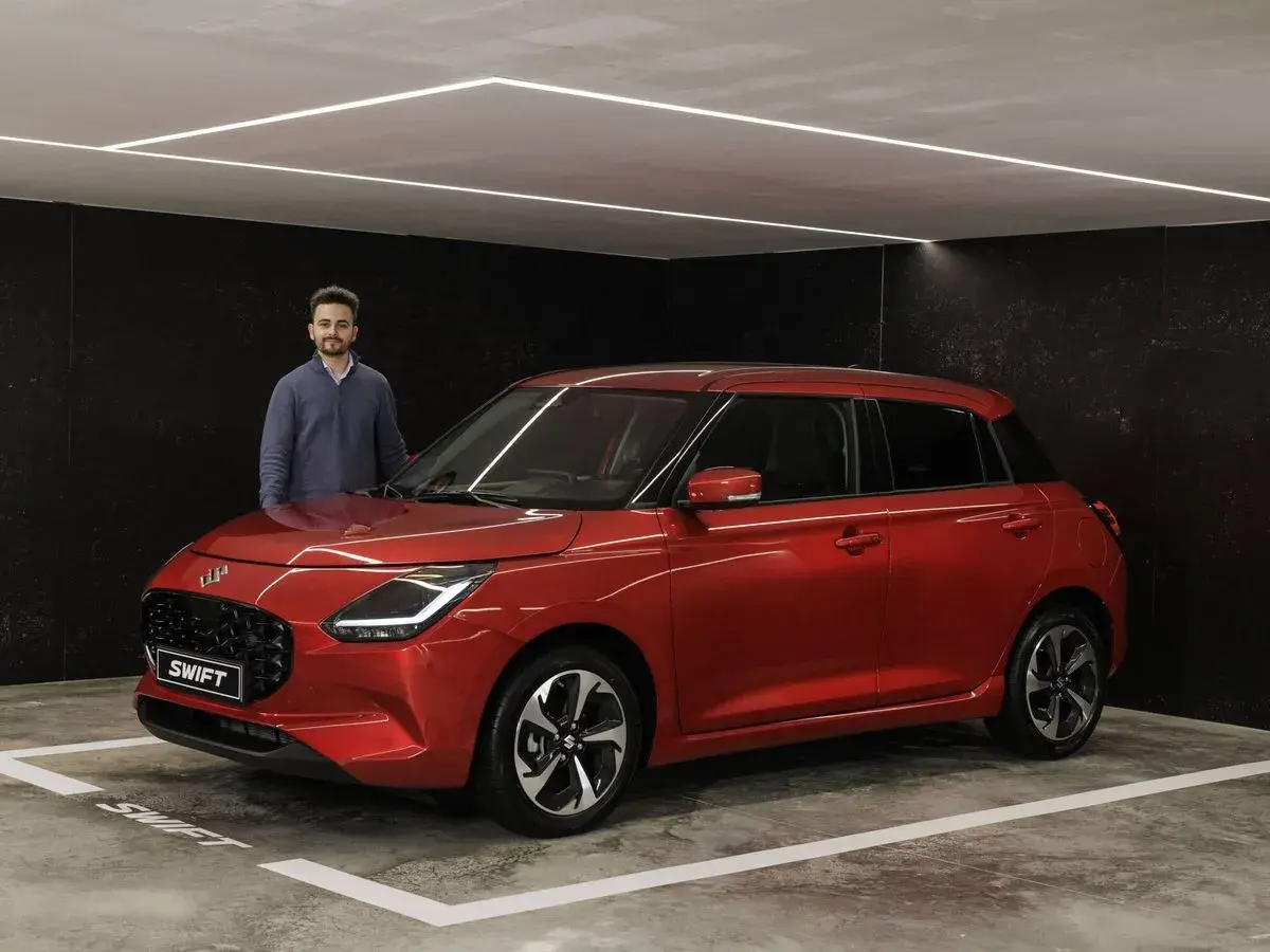 Hombre posando junto a un Suzuki Swift rojo brillante, listo para su prueba.
