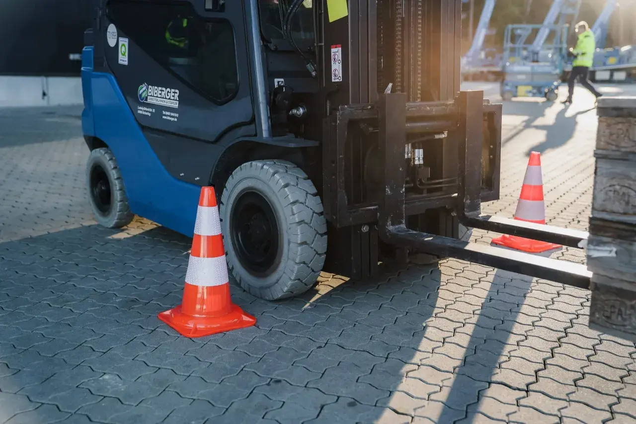 Ein Gabelstapler steht bereit, um zu stapler fahren. Orangefarbene Verkehrskegel markieren den Bereich.