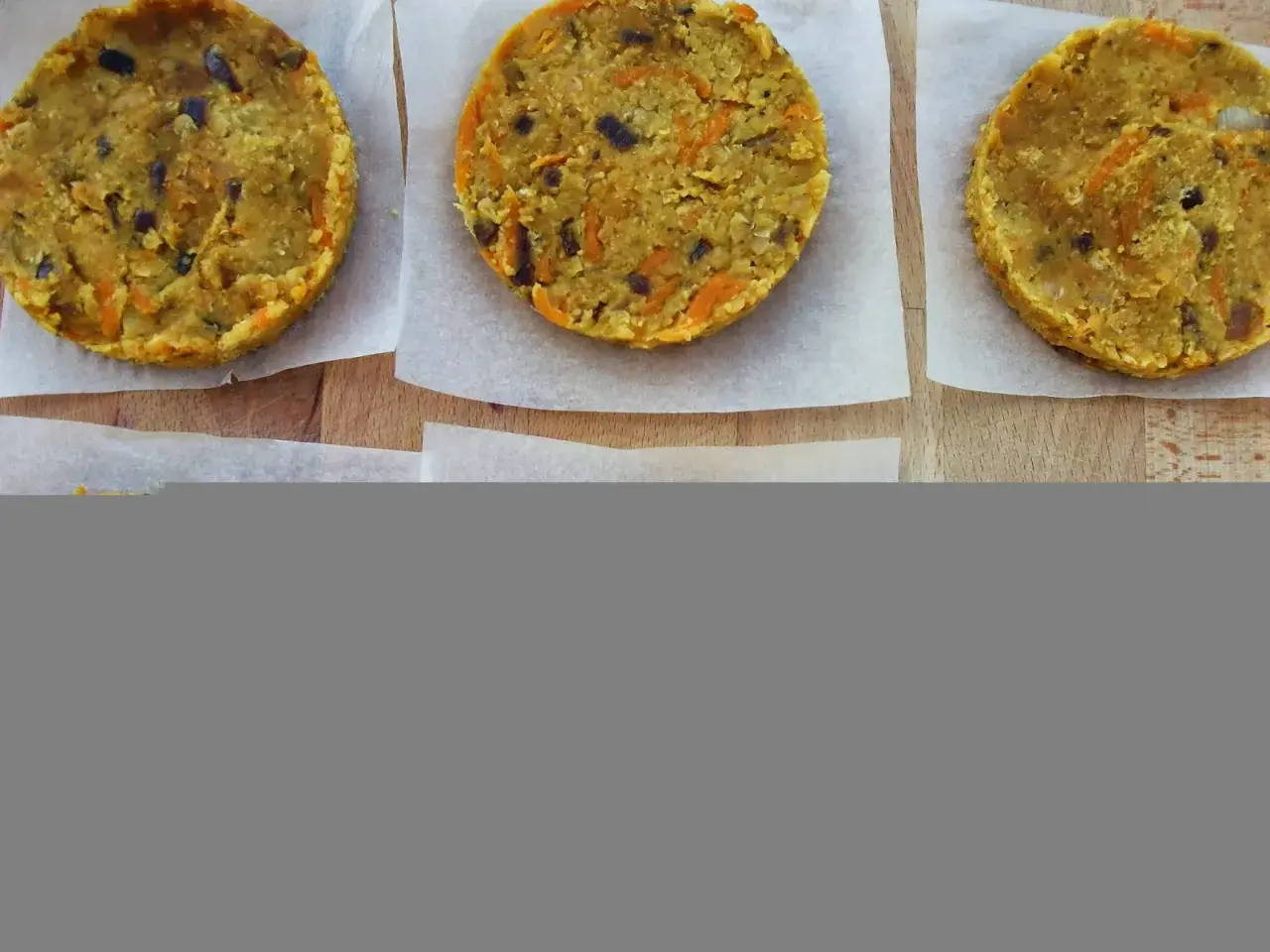 Seis hamburguesas de lentejas caseras, listas para cocinar. Tienen trocitos de zanahoria y cebolla morada.