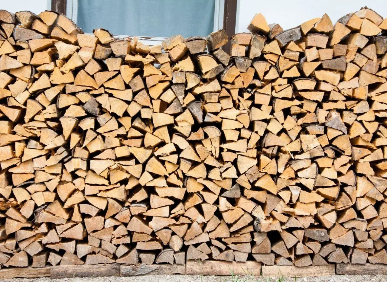 Stos drewna opałowego, gotowy do zapewnienia ciepła. Różne kawałki drewna ułożone w stos, świadczące o jego potencjalnej wartości opałowej.
