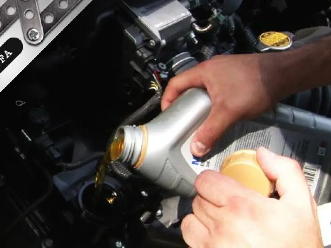 Mano che versa olio motore nel vano del motore. Il tappo giallo indica dove si mette l'olio motore.