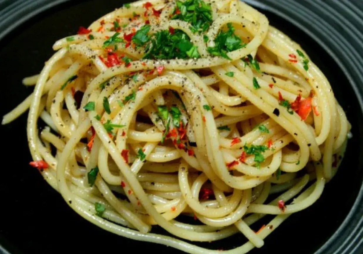Pyszne spaghetti aglio olio, posypane natką pietruszki i płatkami chili. Idealny przepis na szybki obiad.