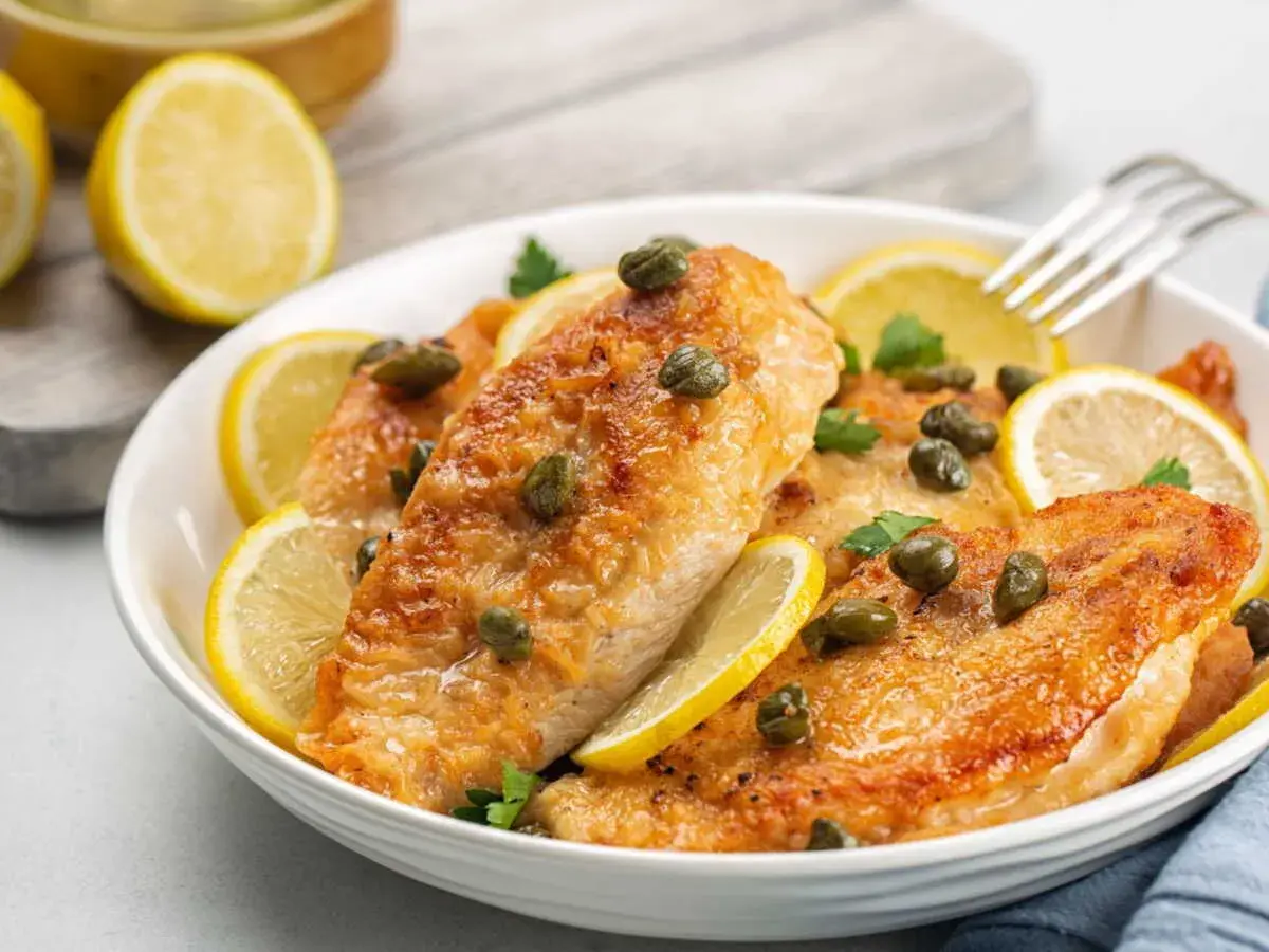 Délicieux poulet au citron, garni de câpres et de rondelles de citron frais, prêt à être dégusté.