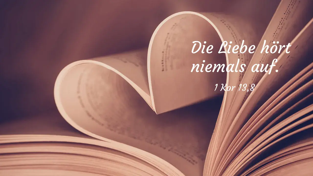 Ein aufgeschlagenes Buch formt ein Herz. Darauf steht: "Die Liebe hört niemals auf. 1 Kor 13,8". Bibelverse über die Liebe für Partner.