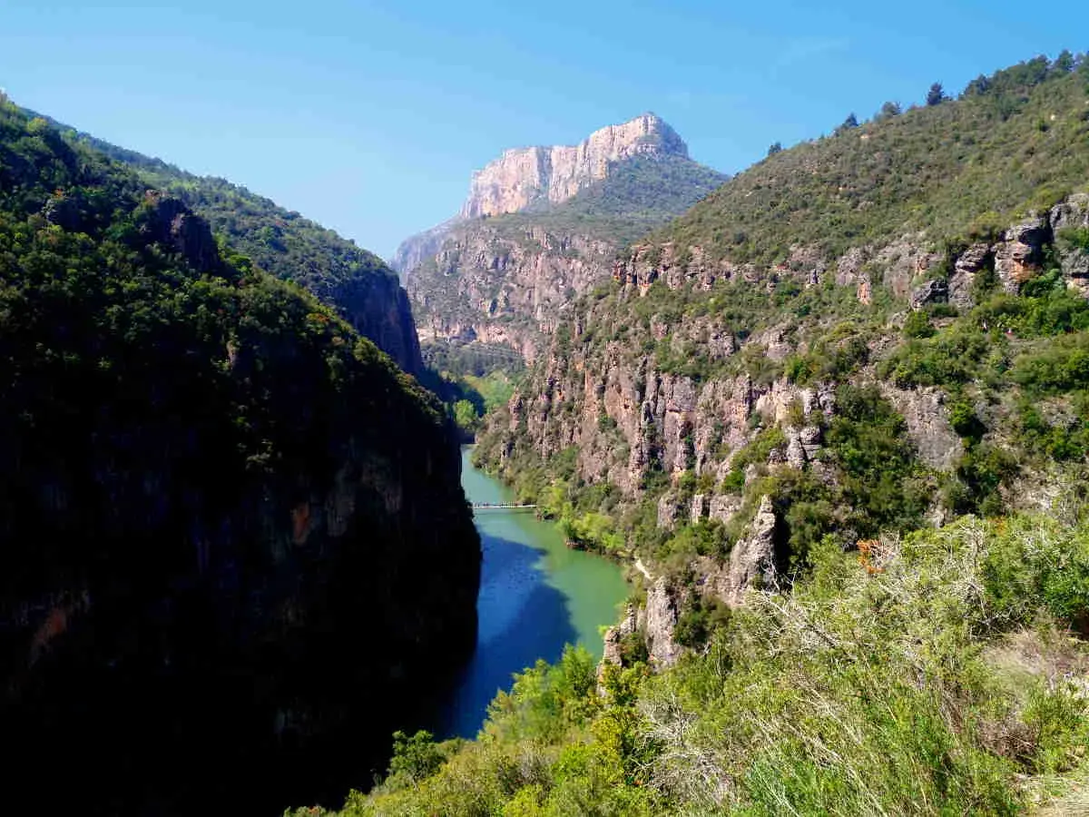 El río serpentea entre imponentes paredes rocosas en el congost del Mu, coronado por un pico montañoso.