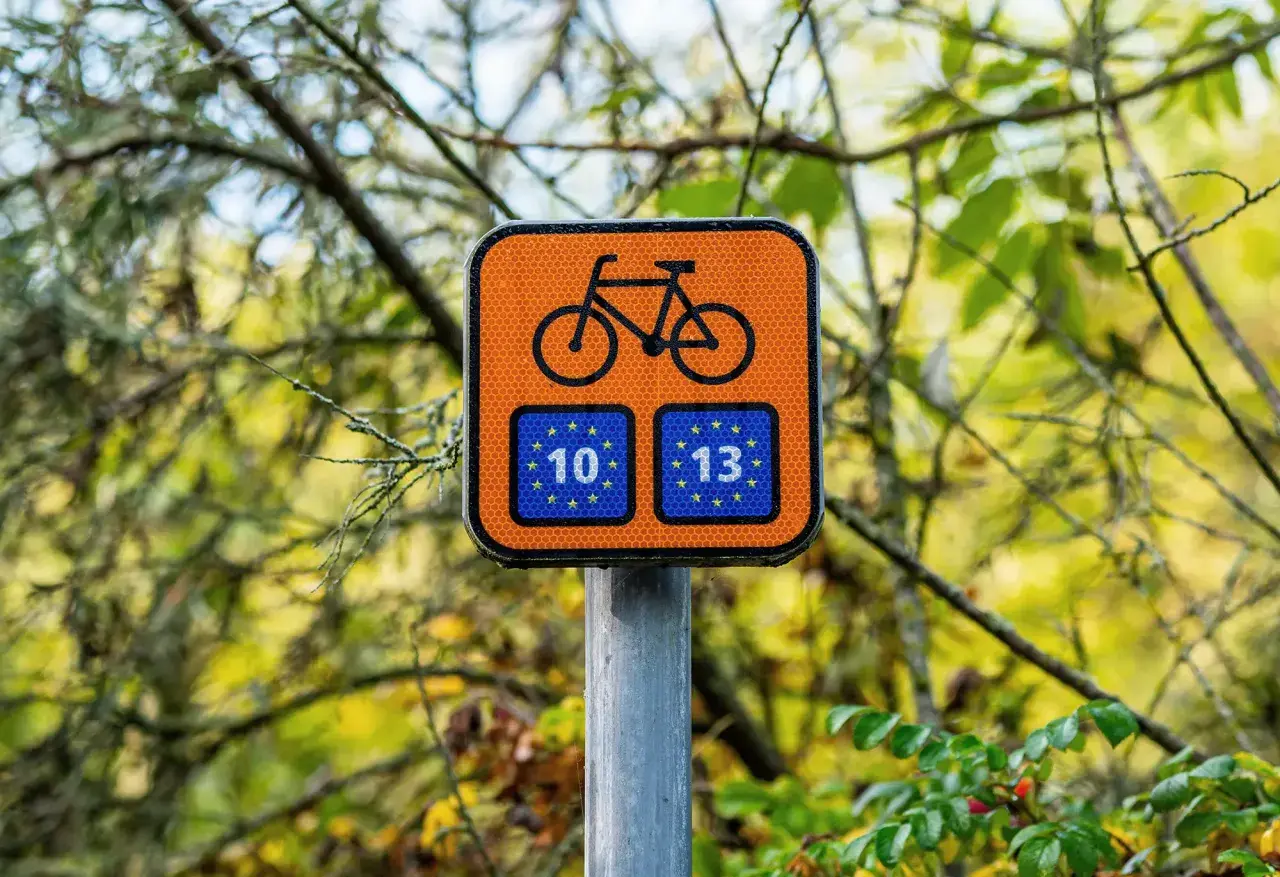 Pomarańczowy znak rowerowy z numerami 10 i 13, wskazujący drogę na trasie rowerowej Świnoujście Hel.
