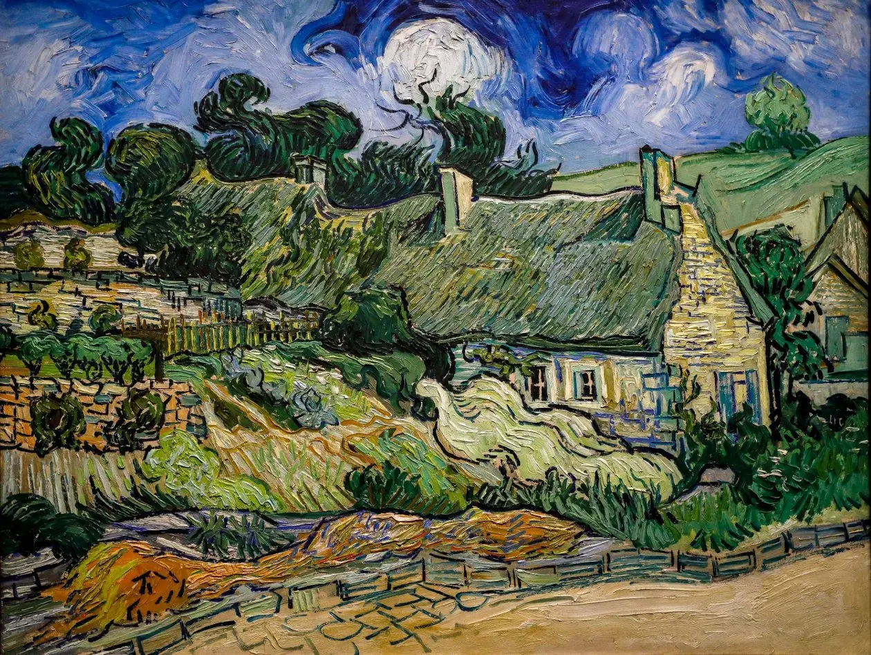 Ein Dorf mit strohgedeckten Häusern und üppiger Vegetation, typisch für die Werke van Goghs. Der Himmel ist dramatisch blau mit wirbelnden Wolken.