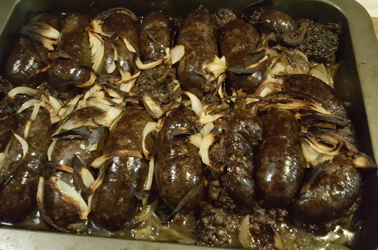 Kaszanka pieczona w piekarniku z cebulą, apetycznie przyrumieniona, gotowa do podania.